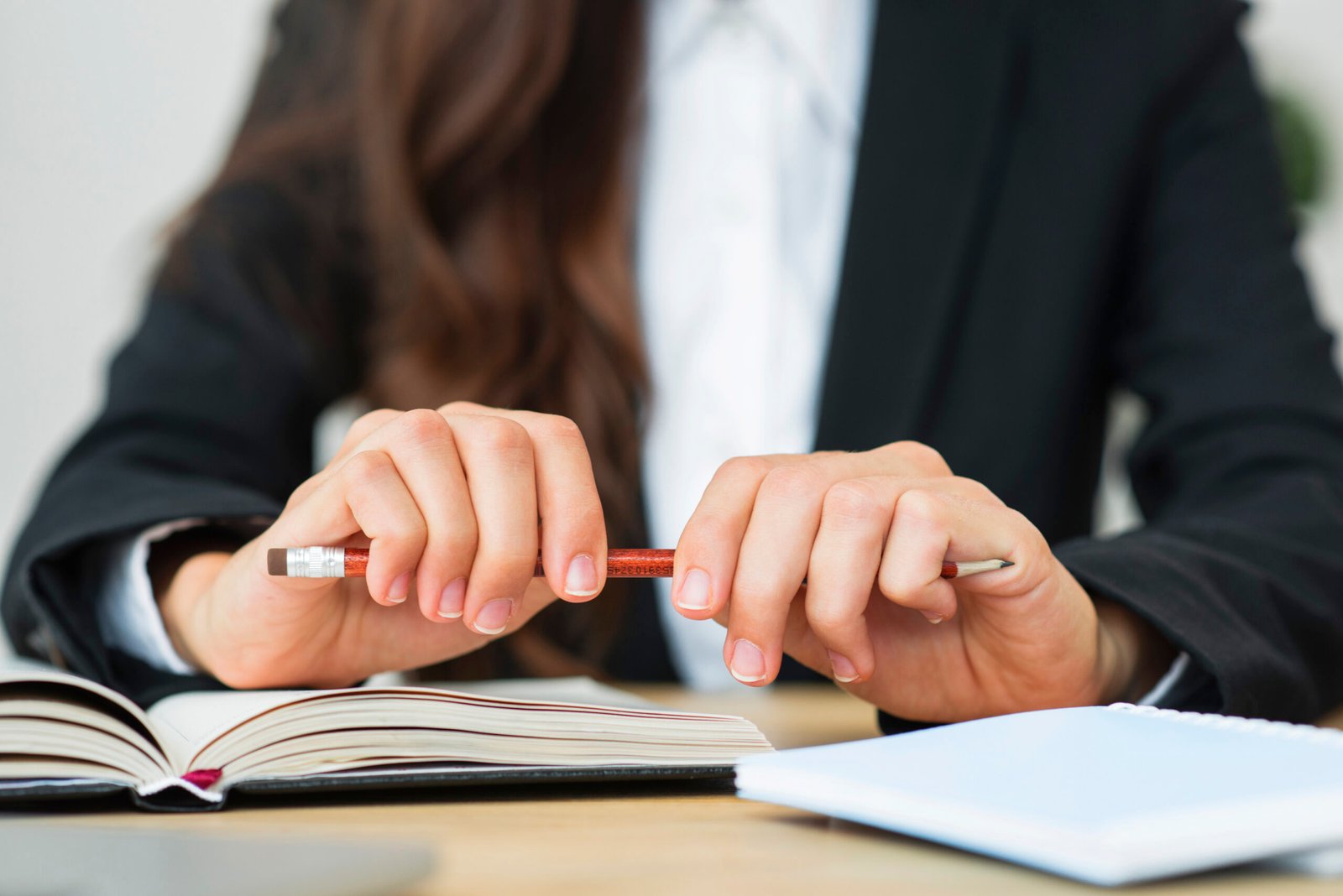 primer-plano-de-una-empresaria-sosteniendo-un-lapiz-rojo-en-sus-dos-manos-sobre-el-escritorio primer-plano-de-una-empresaria-sosteniendo-un-lapiz-rojo-en-sus-dos-manos-sobre-el-escritorio
